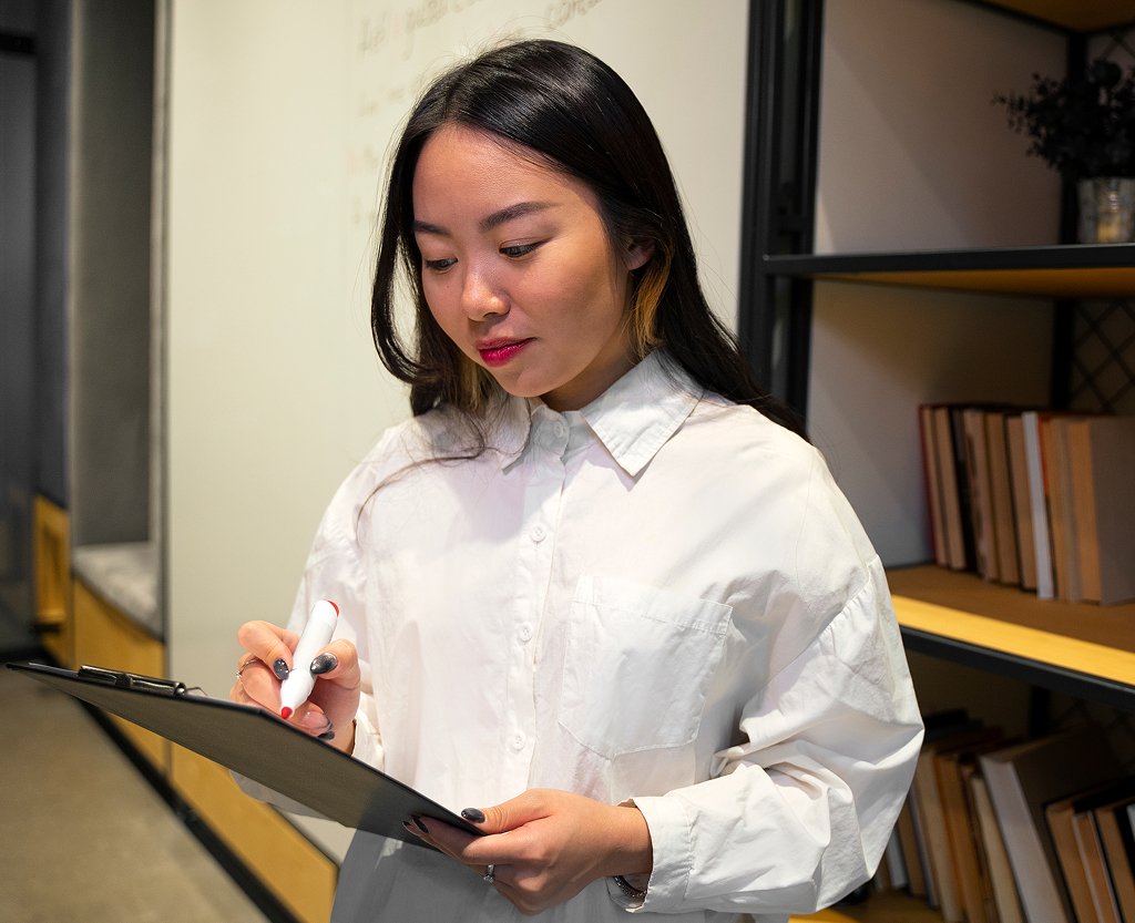 Woman reviewing and correcting written content at her desk — offshore content role